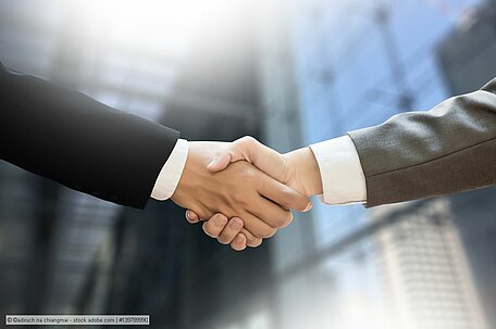 Two men in suits shake hands, representative image