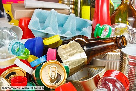 Different types of packaging waste: bottles, beverage cans and food tins, an egg carton. 