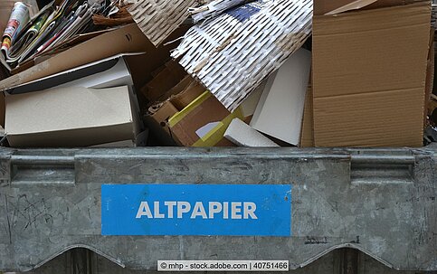 Paper and cardboard in containers with a blue sticker "Altpapier", stockphoto