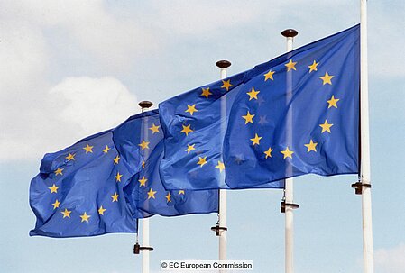 Four flagstaffs in a row flying the EU flag