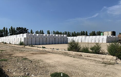 Waste bales wrapped in plastic film stacked on an interim storage site.