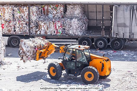 Wheel loader charging a lorry with recovered paper bales