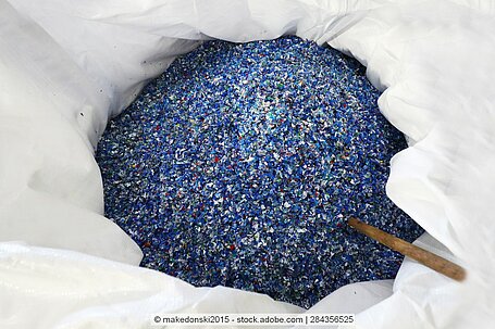 Plastic flakes in mixed colours (mainly shades of blue, grey and white) in a white bag