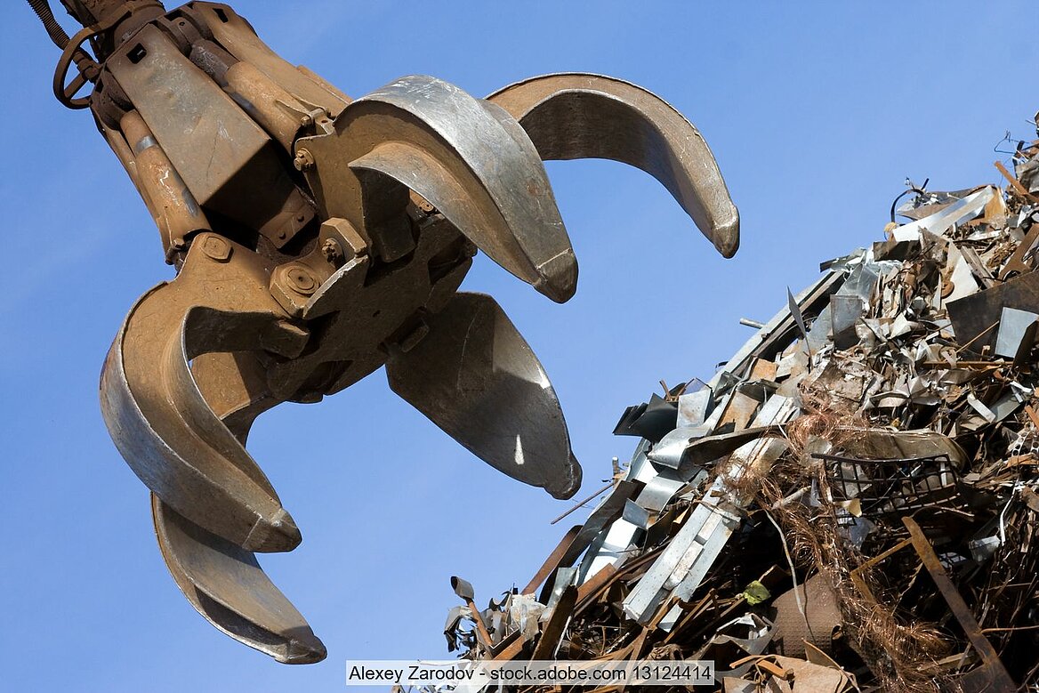 Stock photo of a material handler's opened grab claw above a pile of obsolete scrap.
