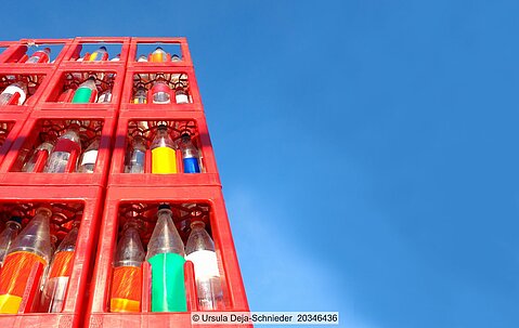 Stack of red beverage crates with empty returnede plastic bottles against a blue sky