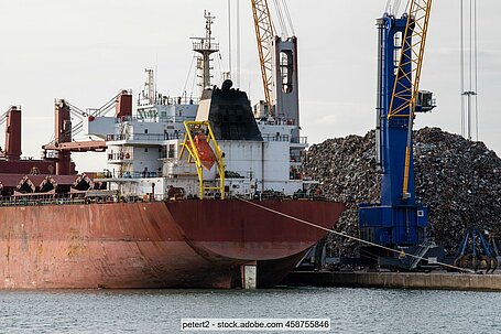 A bulk ship in a port is being loaded with ferrous scrap.