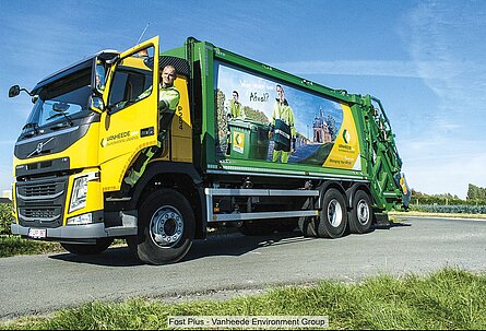 Male driver steps down from the cab of a Vanheede Environment Group refuse collection vehicle (green and yellow livery)