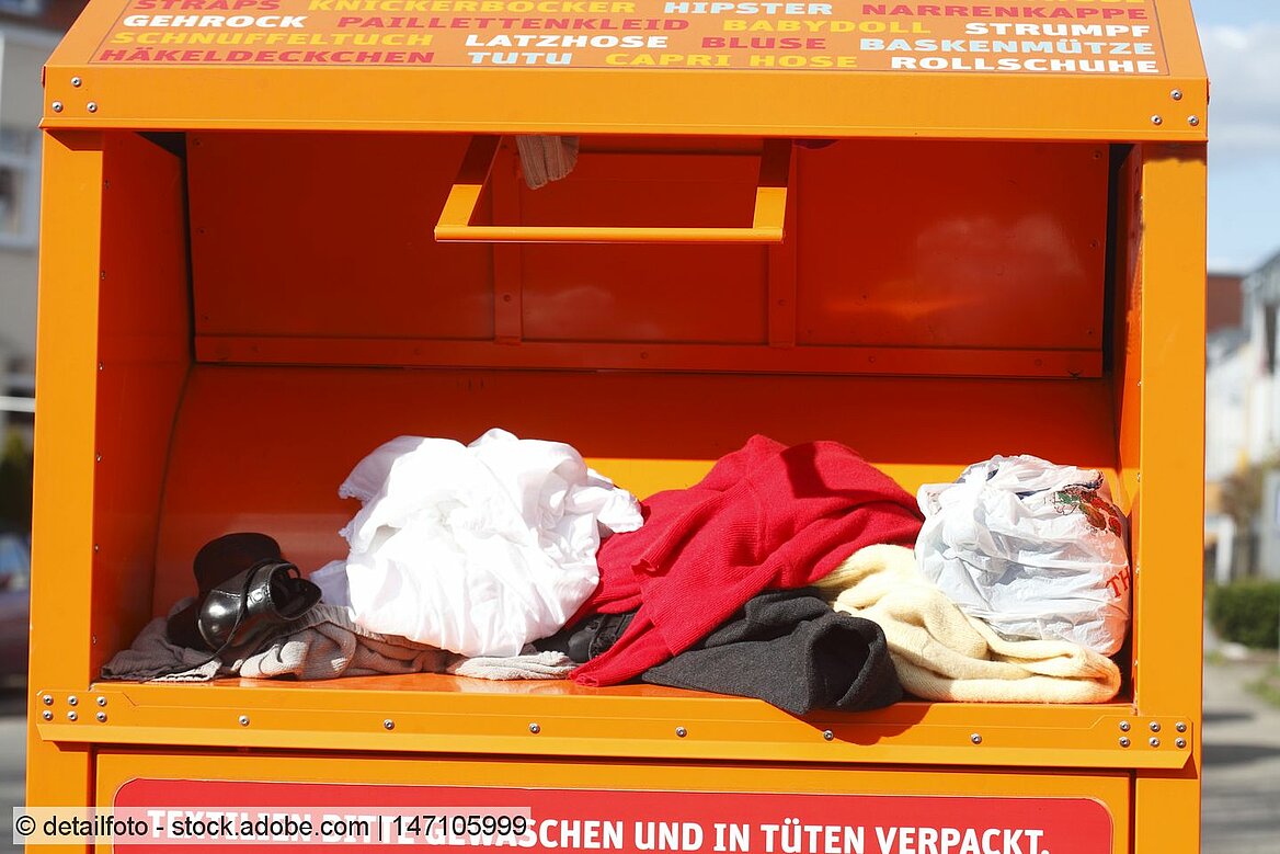 Orange textiles bank with loose clothes and a shoe placed in its chute