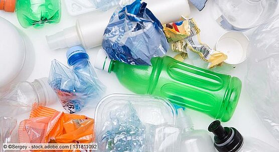 Clear and coloured plastic bottles and other types of plastic packaging in different colours, some of them crushed.