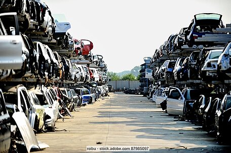 ELVs stacked into long rows of shelves in a scrap yard.