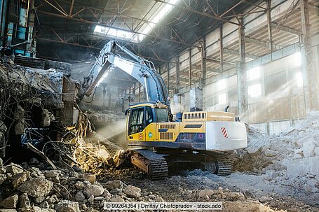 Excavator demolishes a warehouse