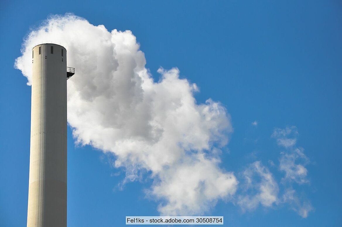 Stock photo of an industrial stack with a white steam plume against blue sky
