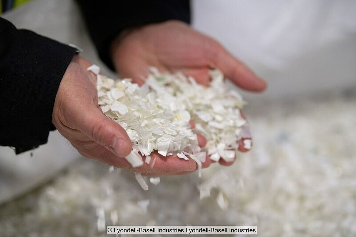 Two hands filled with white plastic flakes against a light background
