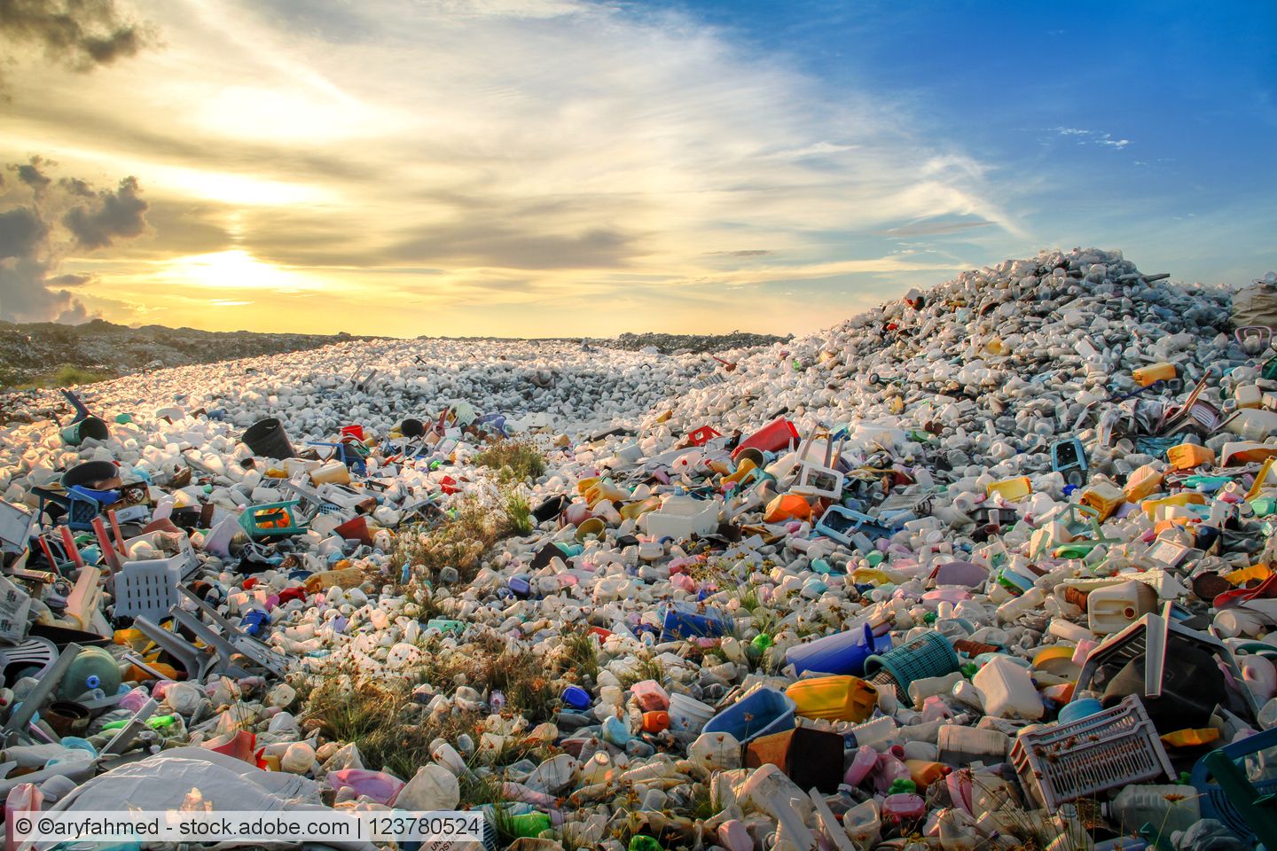 Mounds of mixed waste plastics against a sunset