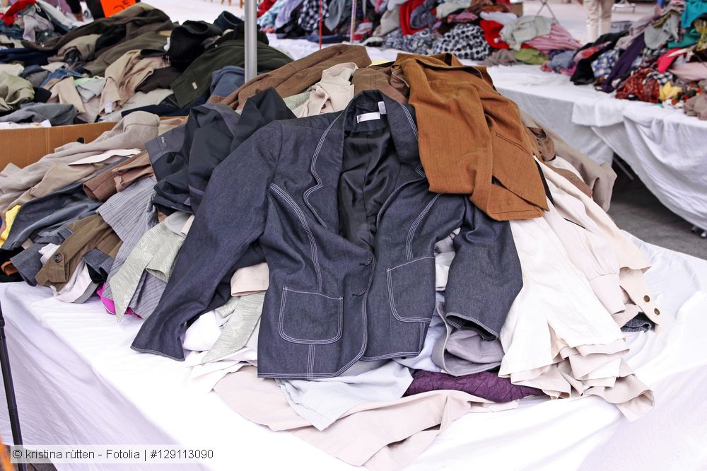 Secondhand clothes displayed for sale on tables.