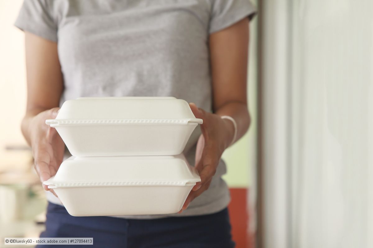 Woman carries stack of two EPS takeaway boxes