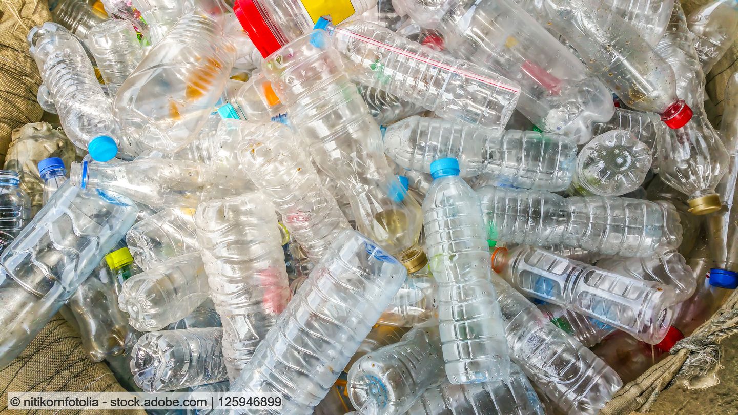 A pile of transparent empty PET bottles with closures in different colours.