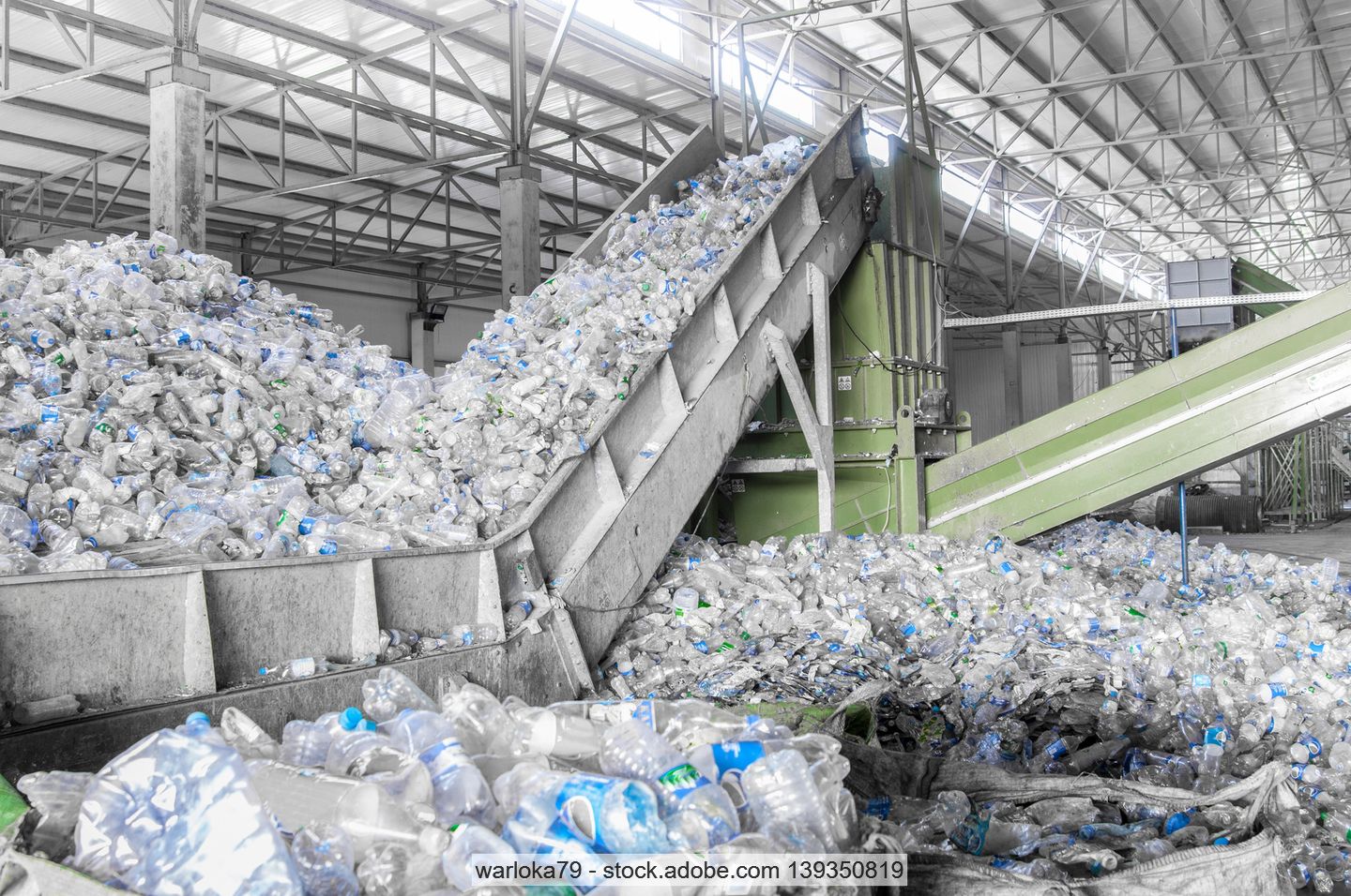 Conveyor in a PET recycling plant filled with clear transparent bottles.