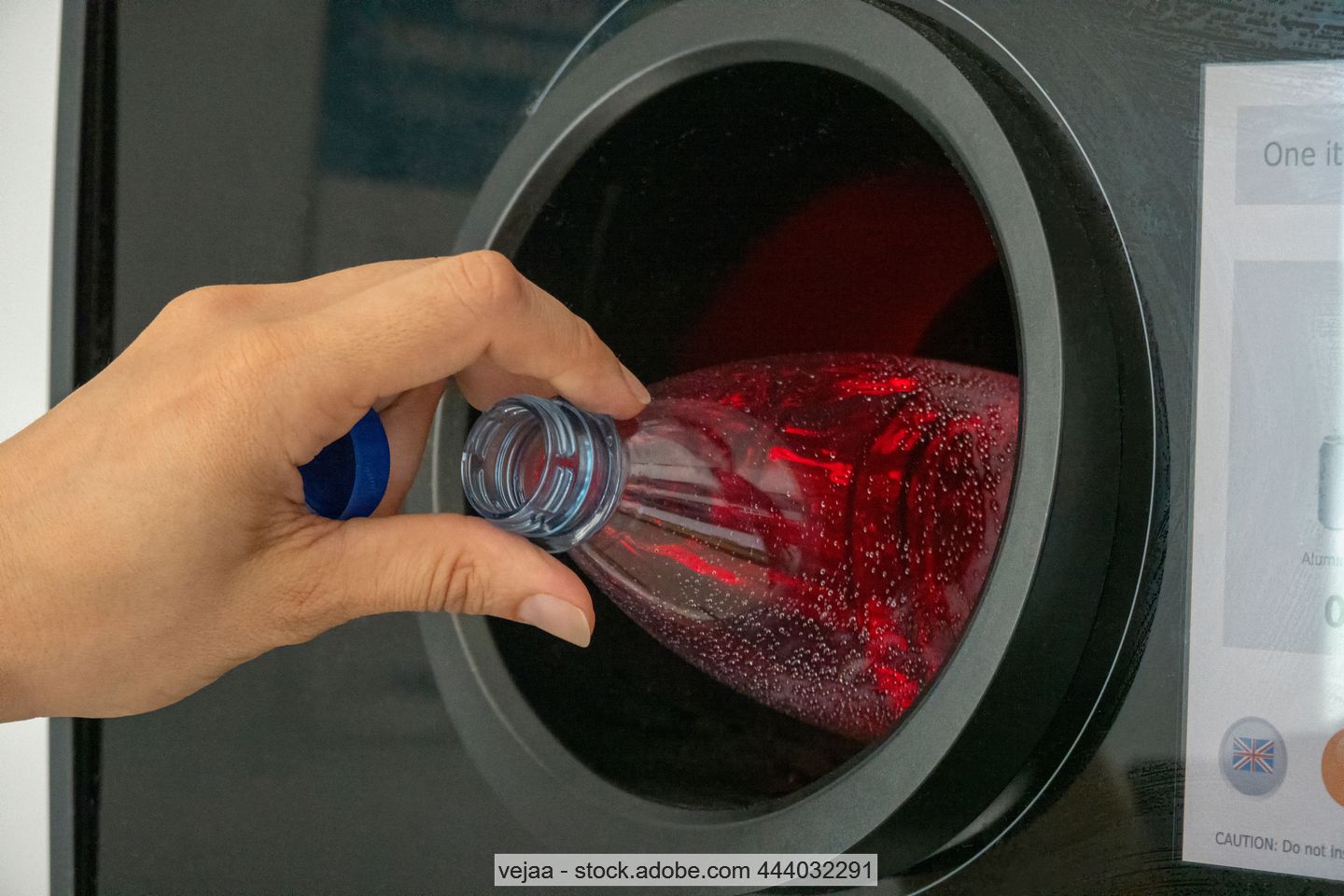 Hand places plastic beverage bottle in reverse vending machine
