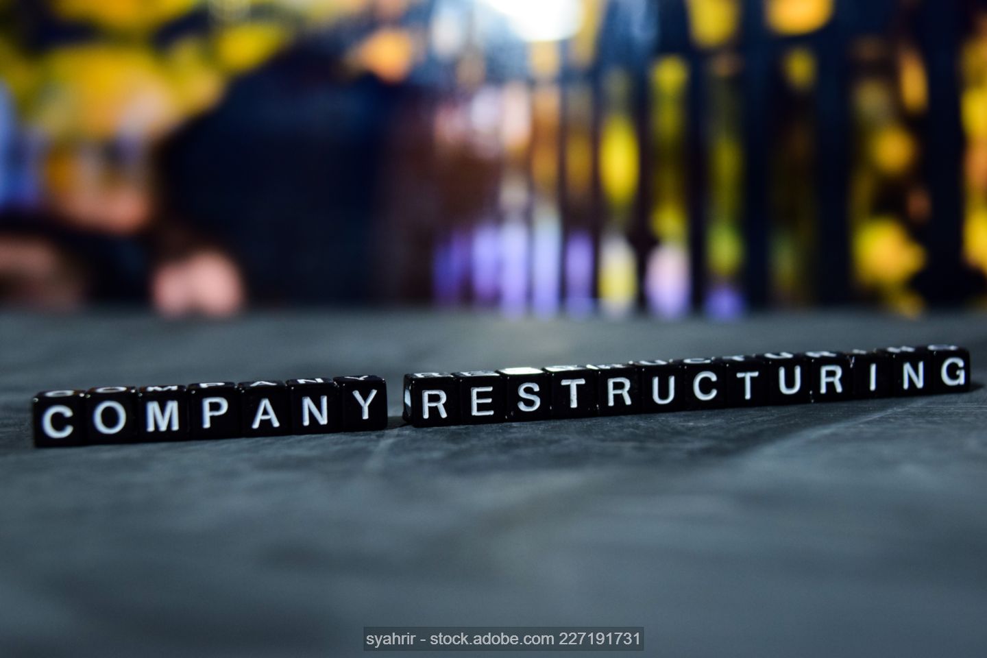 Symbolic photo of a row of black cubes with the inscription "Company restructuring" 