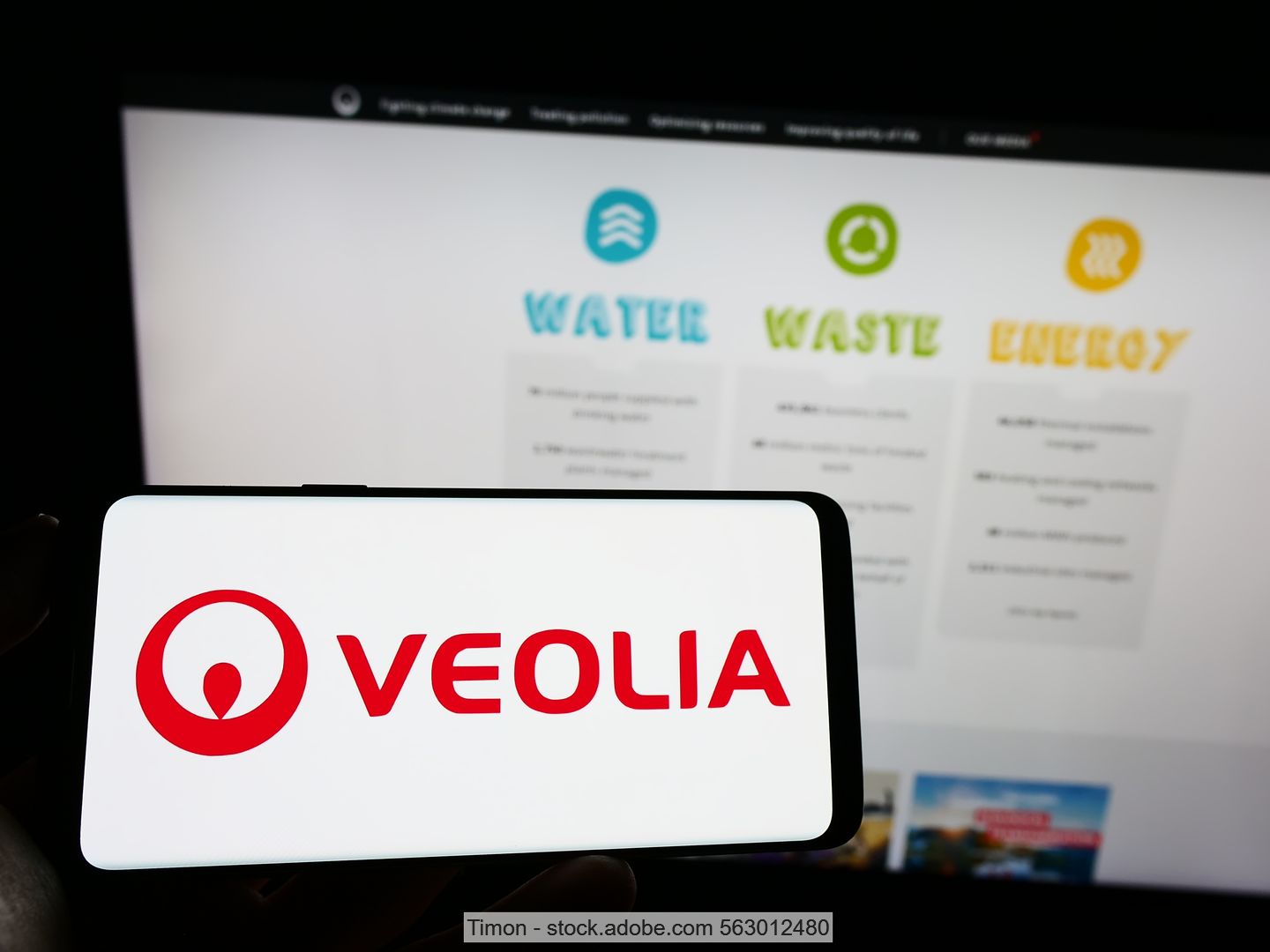 Photo of a computer screen showing the three Veolia divisions: water, waste and energy; in the foreground mobile phone screen with the group‘s logo.